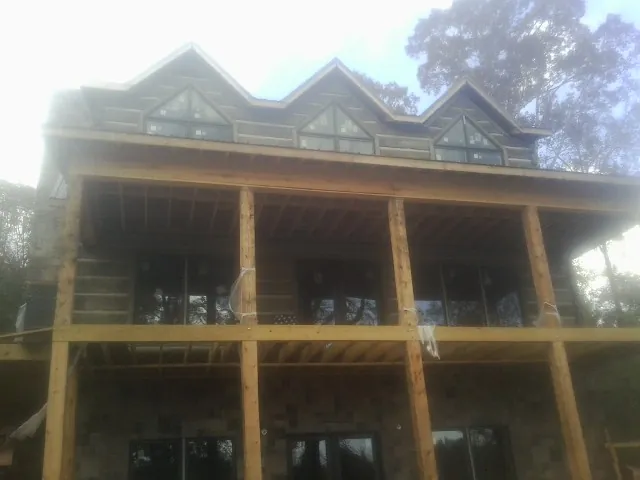 Dormers and porch framing on a large log home under construction — Roof Coating work by our crew in Farmington